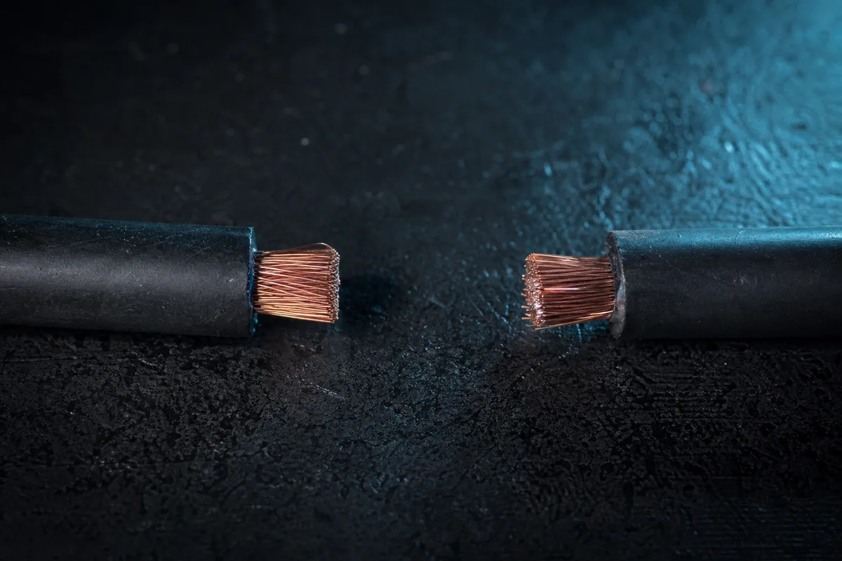 Câble électrique sectionné net posé sur une surface sombre