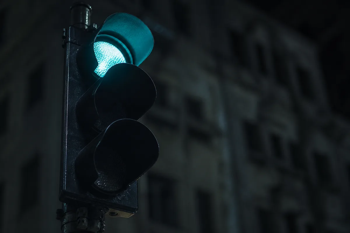 Feu tricolore éteint sauf le signal supérieur, dans une rue nocturne