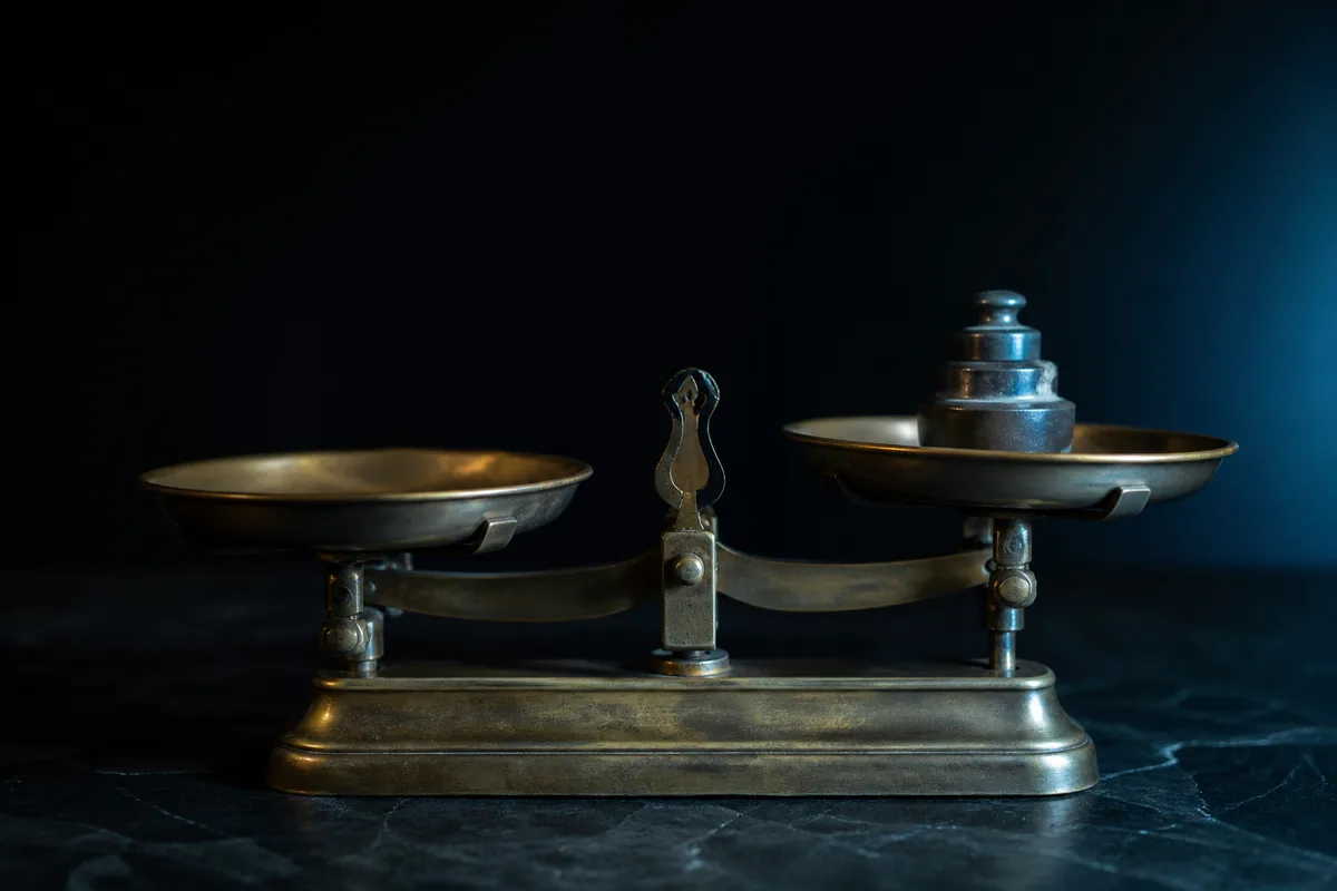 Balance de précision en laiton sur un plan de travail sombre, lumière cyan rasante